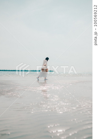 海辺にドライフラワーとカゴを持って佇む女性の写真 100569212