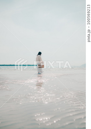 海辺にドライフラワーとカゴを持って佇む女性の写真 100569213