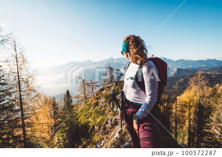 Waist up woman hiker looking away from the camera at a view of the sunny autumn mountains in the background Waist up woman hiker looking away from the camera at a view of the sunny autumn mountains in the background 100572287