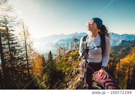 Sunny autumn day up in the mountains and cheerful caucasian woman hiker enjoying the warmth of the sun Sunny autumn day up in the mountains and cheerful caucasian woman hiker enjoying the warmth of the sun 100572289