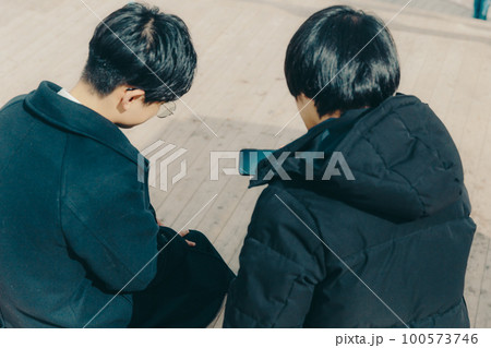 男子大学生が公園でスマホを触っている写真 100573746