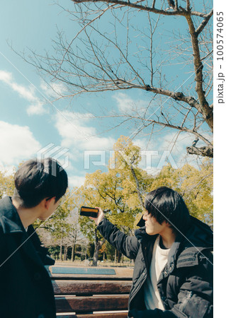 男子大学生が観光先で記念写真を撮っている写真 100574065