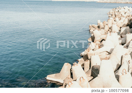 Coast breakwaters protecting from large waves with sea water background. The seashore is reinforced with concrete tetrapods. 100577098