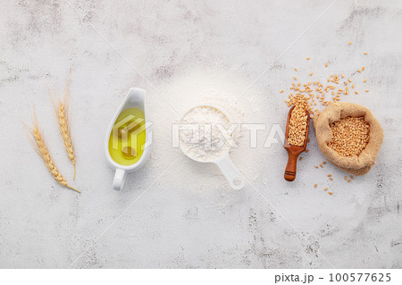 The ingredients for homemade pizza dough with wheat ears ,wheat flour and olive oil set up on white concrete background. top view and copy space. 100577625