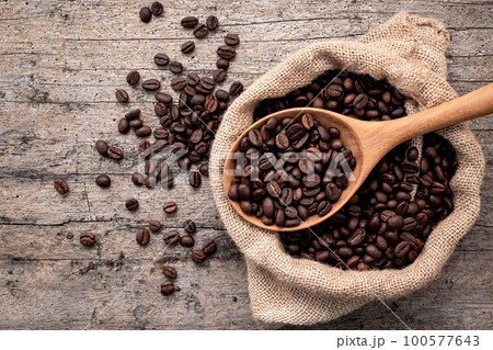 Background of dark roasted coffee beans with scoops setup on wooden background with copy space. Background of dark roasted coffee beans with scoops setup on wooden background with copy space. 100577643