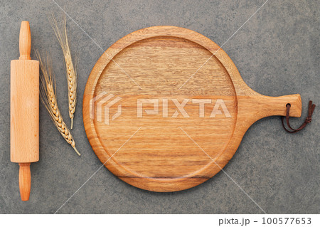 Empty wooden pizza platter set up on dark concrete. Pizza tray on dark concrete background flat lay and copy space. Empty wooden pizza platter set up on dark concrete. Pizza tray on dark concrete background flat lay and copy space. 100577653