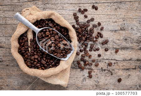 Background of dark roasted coffee beans with scoops setup on wooden background with copy space. 100577703