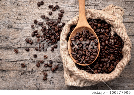 Background of dark roasted coffee beans with scoops setup on wooden background with copy space. Background of dark roasted coffee beans with scoops setup on wooden background with copy space. 100577909