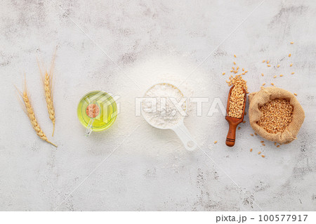 The ingredients for homemade pizza dough with wheat ears ,wheat flour and olive oil set up on white concrete background. top view and copy space. The ingredients for homemade pizza dough with wheat ears ,wheat flour and olive oil set up on white concrete background. top view and copy space. 100577917