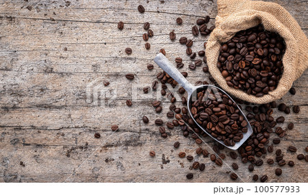 Background of dark roasted coffee beans with scoops setup on wooden background with copy space. 100577933