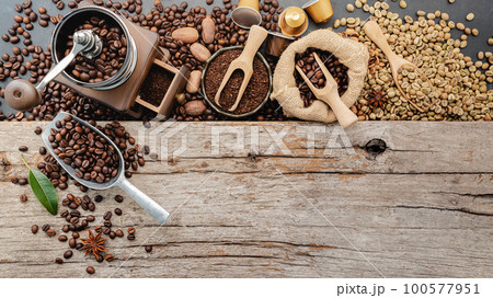 Background of various coffee , dark roasted coffee beans , ground and capsules with scoops setup on wooden background with copy space. 100577951