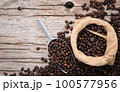 Background of dark roasted coffee beans with scoops setup on wooden background with copy space. 100577956