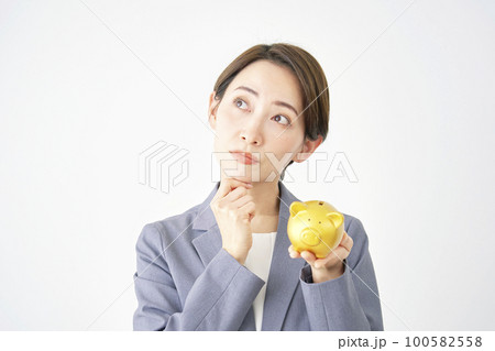 豚の貯金箱を持って考えるビジネスウーマン 白背景 豚の貯金箱を持って考えるビジネスウーマン 白背景 100582558