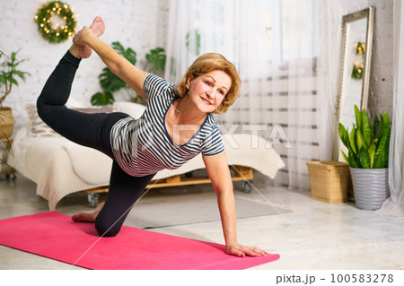 Mature woman doing sports on mat at home 100583278