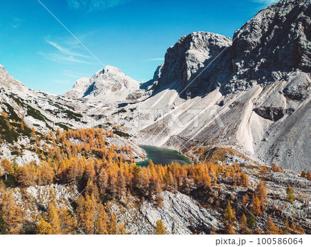 Scree slopes under mountain tops and a small lake in the valley of Triglav national park Scree slopes under mountain tops and a small lake in the valley of Triglav national park 100586064