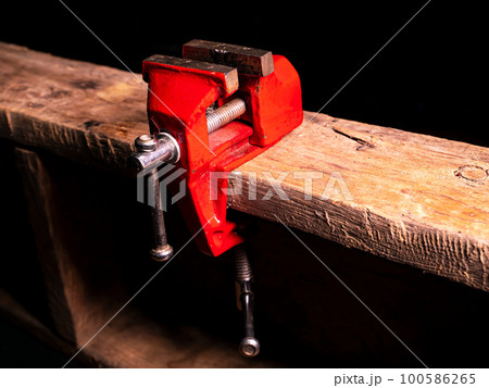 Locksmiths tool metal vise fixed on a wooden table. 100586265