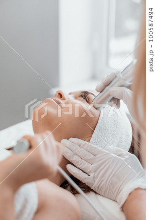 Electroporation without injection mesotherapy. Woman cosmetologist performs cosmetic procedure Electroporation without injection mesotherapy. Woman cosmetologist performs cosmetic procedure 100587494
