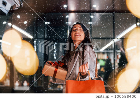 Near the car with gift box. Cheerful woman is outdoors at Christmas holidays time. Conception of new year 100588400