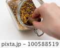 close up of a hand holding a spoon of seeds 100588519