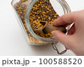 close up of a hand holding a spoon of seeds 100588520
