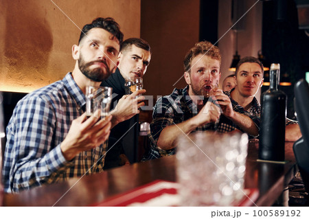 Expressive people watching soccer. Group of people together indoors in the pub have fun at weekend time Expressive people watching soccer. Group of people together indoors in the pub have fun at weekend time 100589192