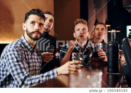 Expressive people watching soccer. Group of people together indoors in the pub have fun at weekend time Expressive people watching soccer. Group of people together indoors in the pub have fun at weekend time 100589193