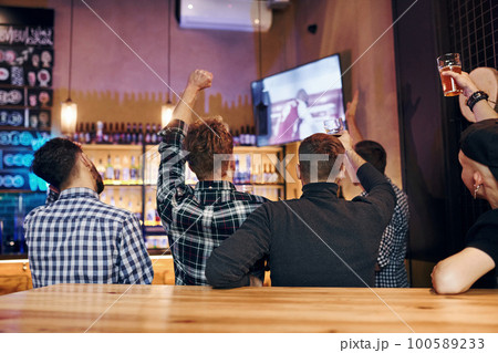 Football fans watching TV. Group of people together indoors in the pub have fun at weekend time 100589233