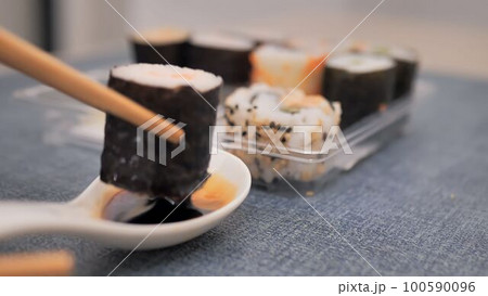 take a roll with chopsticks and dip it in soy sauce take a roll with chopsticks and dip it in soy sauce 100590096