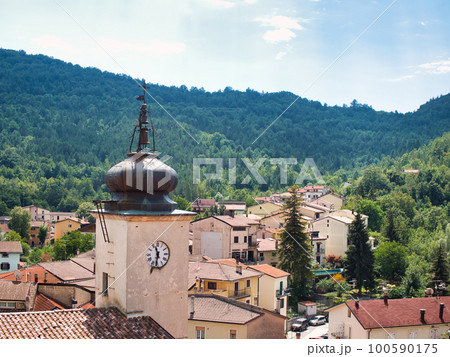 a clock tower in a town in the mountains of Italy. 100590175