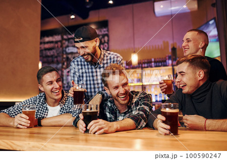 Football fans watching TV. Group of people together indoors in the pub have fun at weekend time 100590247
