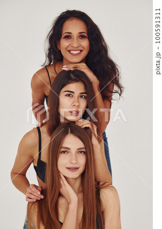 Three young women in lingerie together indoors. White background Three young women in lingerie together indoors. White background 100591311