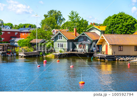 Small harbor with typical picturesque scandinavian wooden houses on a sunny day. Island of Vaxholm, Stockholm Archipelago, Sweden 100592794