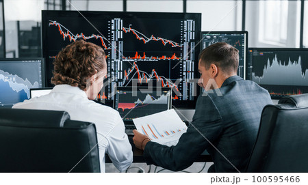 Conception of teamwork. Team of stockbrokers works in modern office with many display screens 100595466