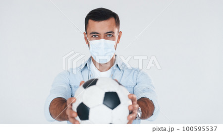 Football fan with soccer ball. Young handsome man standing indoors against white background Football fan with soccer ball. Young handsome man standing indoors against white background 100595537