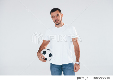 Football fan with soccer ball. Young handsome man standing indoors against white background Football fan with soccer ball. Young handsome man standing indoors against white background 100595546