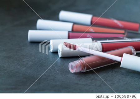 Liquid lipstick or lip gloss with open tube on stone background 100598796