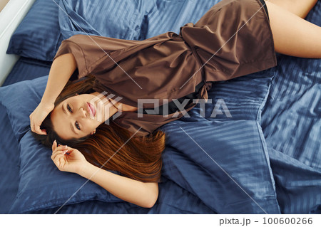 Young woman lying down and resting. Interior and design of beautiful modern bedroom at daytime 100600266