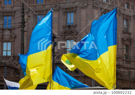 Flag with yellow and blue striped colors of Ukraine waving in the wind with a blue sky and sun. 100602232