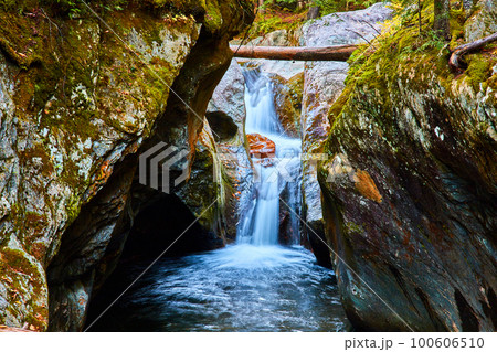 Narrow gorge eye level to waterfall raging down with mossy rocks 100606510