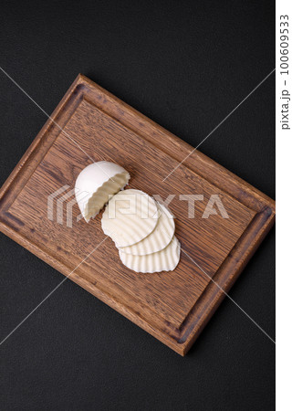 Delicious fresh mozzarella cut into slices on a wooden cutting board Delicious fresh mozzarella cut into slices on a wooden cutting board 100609533