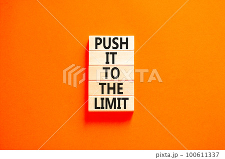 Push it to the limit symbol. Concept words Push it to the limit on wooden blocks. Beautiful orange table orange background. Business push it to the limit concept. Copy space. 100611337