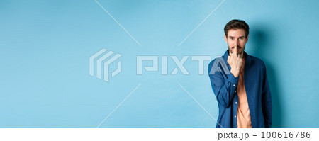 Ignorant and rude guy showing middle finger and smiling, say fuck you, standing on blue background 100616786