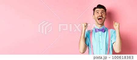 Relieved and happy man thanking god, looking up in sky while celebrating victory, winning prize and cheering, triumphing over pink background Relieved and happy man thanking god, looking up in sky while celebrating victory, winning prize and cheering, triumphing over pink background 100618363