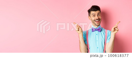 Handsome funny guy pointing fingers aside, showing left and right logo and smiling, recommending two choices, standing on pink background Handsome funny guy pointing fingers aside, showing left and right logo and smiling, recommending two choices, standing on pink background 100618377