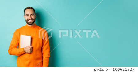 Handsome freelancer man holding laptop and smiling, standing happy over light blue background Handsome freelancer man holding laptop and smiling, standing happy over light blue background 100621527