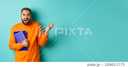 Education. Confused and disappointed man arguing, holding notebooks and complaining, standing over light blue background Education. Confused and disappointed man arguing, holding notebooks and complaining, standing over light blue background 100621775
