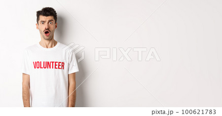 Shocked and confused man in volunteer t-shirt staring at camera speechless, standing against white background Shocked and confused man in volunteer t-shirt staring at camera speechless, standing against white background 100621783
