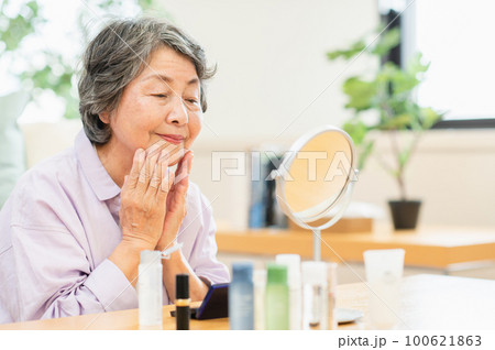 顔に化粧水を塗るシニア女性 100621863