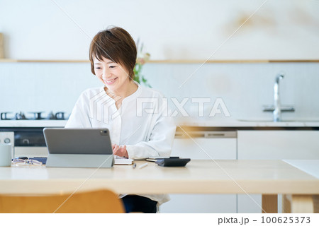 自宅のダイニングキッチンで仕事をする女性 自宅のダイニングキッチンで仕事をする女性 100625373