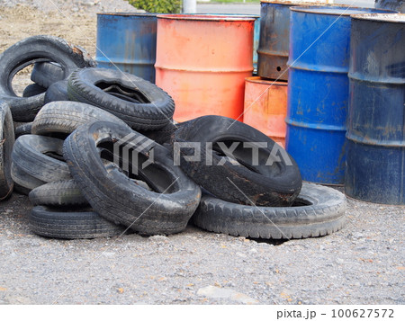 空き地に置かれた古いドラム缶と古タイヤ 100627572